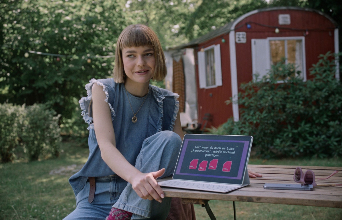 Mädchen im Garten am Gartentisch mit Laptop.